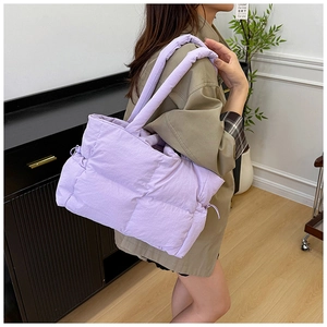 Detailed side view of a large light purple quilted nylon tote bag with wide straps