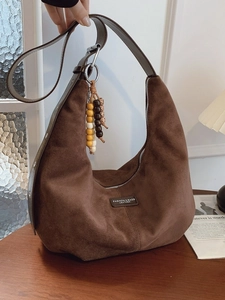 Brown faux suede hobo bag with beaded tassel and shoulder strap in warm vintage setting