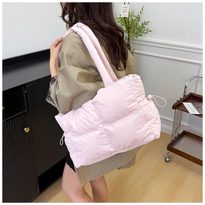 Pink quilted nylon tote bag with drawstring side detail shown on shoulder of a model