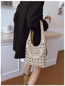 Detail of beige suede hobo bag with silver metallic studs shown on model's shoulder