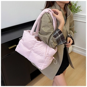 Detail of pink quilted puffer tote bag featuring drawstring sides and padded shoulder straps