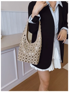 Close-up of beige suede bucket bag with silver rivet studs for a punk rock look