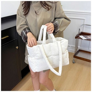 Close-up of white quilted tote bag featuring padded nylon texture and drawstring detail