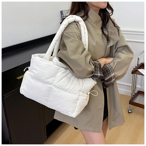 Close-up of white quilted shoulder bag with thick padded strap and drawstring side detail