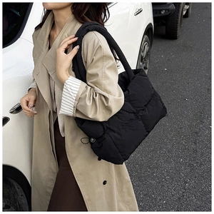 Detail of black quilted puffer tote bag with adjustable drawstring on nylon shoulder strap