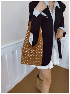 Brown suede hobo bag with silver studs worn by model over a black blazer for a punk look