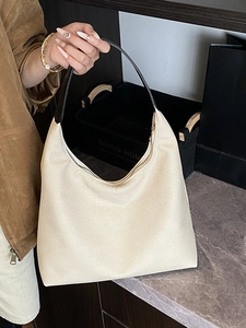 Minimalistische beige Hobo-Tasche mit schwarzen Griffen in stilvollem Innenraum