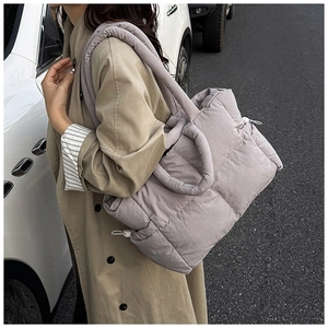Quilted light purple down tote bag worn crossbody in an outdoor street style setting