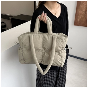 Detail of beige quilted nylon tote bag featuring padded grid texture and side drawstring