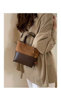 Detail of contrast stitch bucket bag with suede texture and decorative side tassel