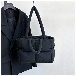 Close-up of black quilted nylon tote bag with puffer texture and dual strap detail