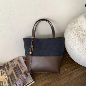 Detail of stitched leather bucket bag featuring blue suede and brown leather texture