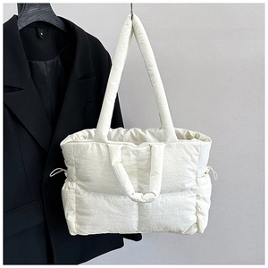 Detailed view of white quilted nylon tote bag with drawstring side and padded texture