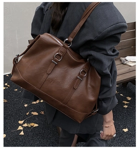 Detailed view of brown retro tote bag with silver metal rings on a leather shoulder strap