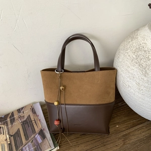 Detail of retro color-block tote bag with suede texture and decorative beaded charm