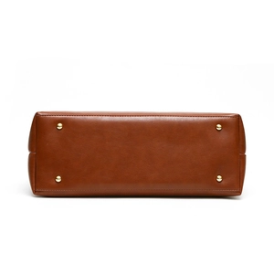 Bottom view of brown leather tote bag showing four gold metal protective feet studs