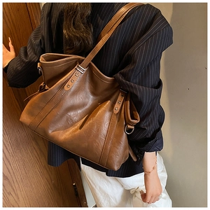 Sac fourre-tout en cuir marron avec rivets en étoile et bandoulière sur modèle
