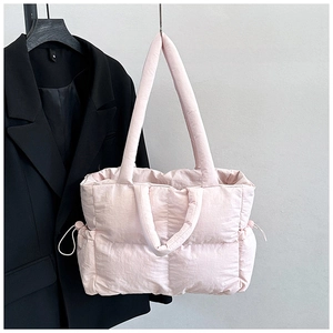 Detail of light pink quilted tote bag with dual straps and stylish side drawstring