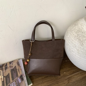 Detail of suede and leather bucket bag featuring NO FILTER embossing and beaded charm