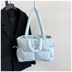 Close-up of light blue quilted tote bag with dual handles and side drawstring detail