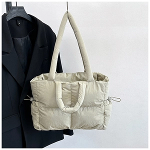 Detail of beige quilted nylon tote bag with puffer texture and drawstring side design