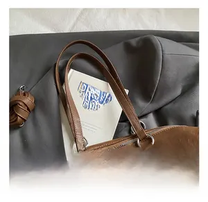 Close-up of brown pebbled leather tote featuring silver metal rings and detachable strap