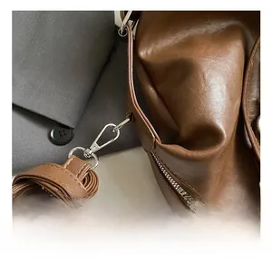 Macro detail of high-gloss silver metal hook and zipper on a brown leather tote bag