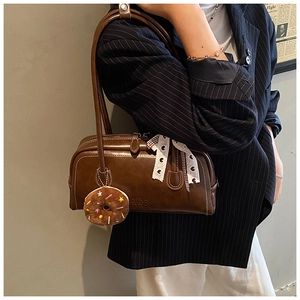 Detail of dark brown leather Boston bag with plush donut charm and lace ribbon