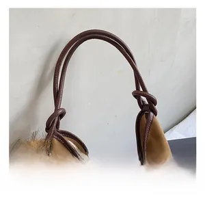 Detail of soft brown suede tote bag featuring a leather knot handle and lion plush charm