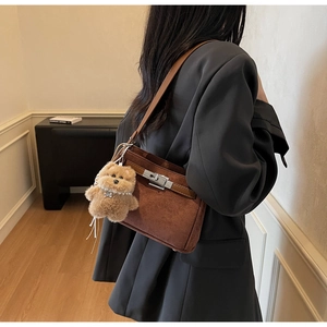 Brown faux suede underarm bag detail featuring silver buckle and cute plush bear charm