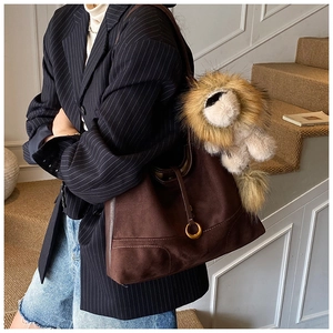 Detail of dark brown faux suede tote bag with golden ring and plush lion charm