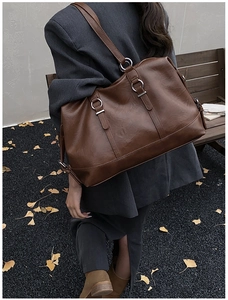 Detailed view of brown vintage leather tote bag with silver hardware and spacious side buckles