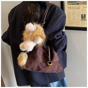 Detail of matte brown tote bag with lion plush keychain and metal ring accessory