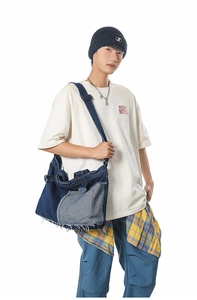 Detail of vintage denim patchwork crossbody bag with utility pockets and raw fringe edges