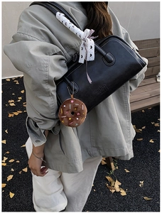 Detail of black leather shoulder bag with white stitching and lace ribbon handle
