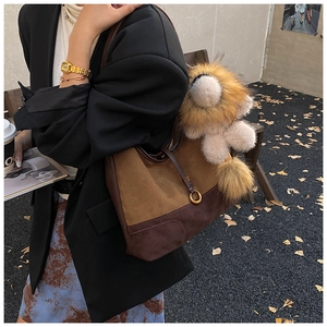 Close-up of brown suede tote bag with drawstring detail and lion plush charm decoration