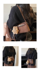 Detail of matte brown crossbody bag with silver buckle and plush bear charm