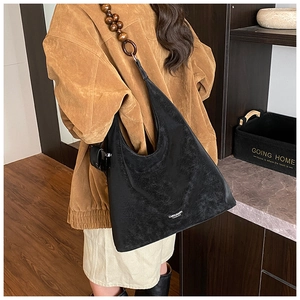 Detail of black matte leather tote bag featuring a vintage wooden bead shoulder strap
