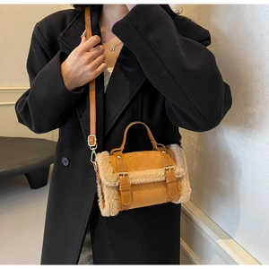 Detail view of brown suede handbag with faux fur trim and adjustable leather strap