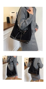 Detail view of large black tote bag featuring spliced textures and long ribbon bow decoration