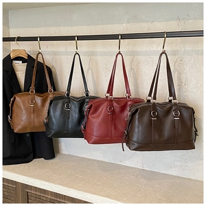 Close-up of vintage tote bags in four colors hanging on a minimalist textured wall
