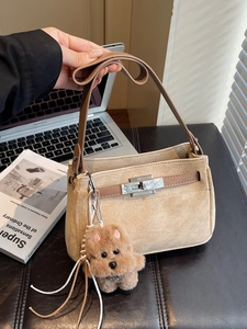 Minimalist beige suede underarm Kelly bag with brown leather strap and dog pendant
