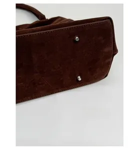 Détail du fond d'un sac cabas vintage marron avec pieds en métal et surpiqûres