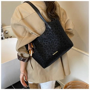 Détail du sac cabas noir à texture léopard avec pendentif en bois et logo doré