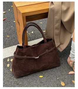 Détail de la texture en cuir suédé mat et de la boucle sur un sac fourre-tout marron