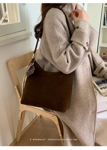 Détail du sac hobo en daim marron foncé avec charme sur un manteau en laine grise
