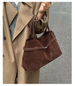 Détail du cabas en daim marron foncé avec boucle décorative sur le cuir texturé élégant