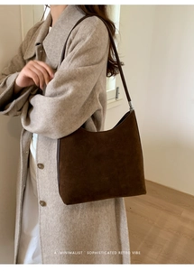 Detail showing deep brown suede hobo bag with silver strap on beige wool coat