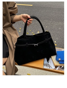 Gros plan d'un sac cabas en daim noir avec boucle métallique sur un banc de rue