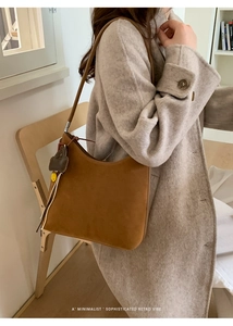 Sac hobo en daim marron avec breloque coeur porté par un mannequin en intérieur